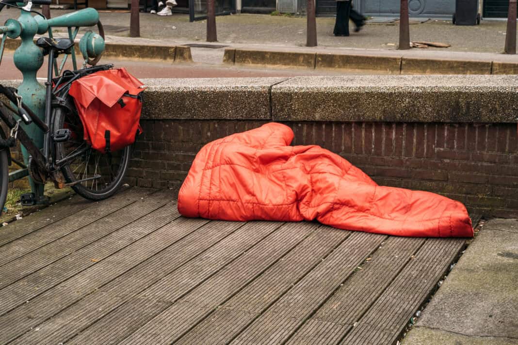 photo-of-a-homeless-person-sleeping-in-a-red-blanket-on-the-street