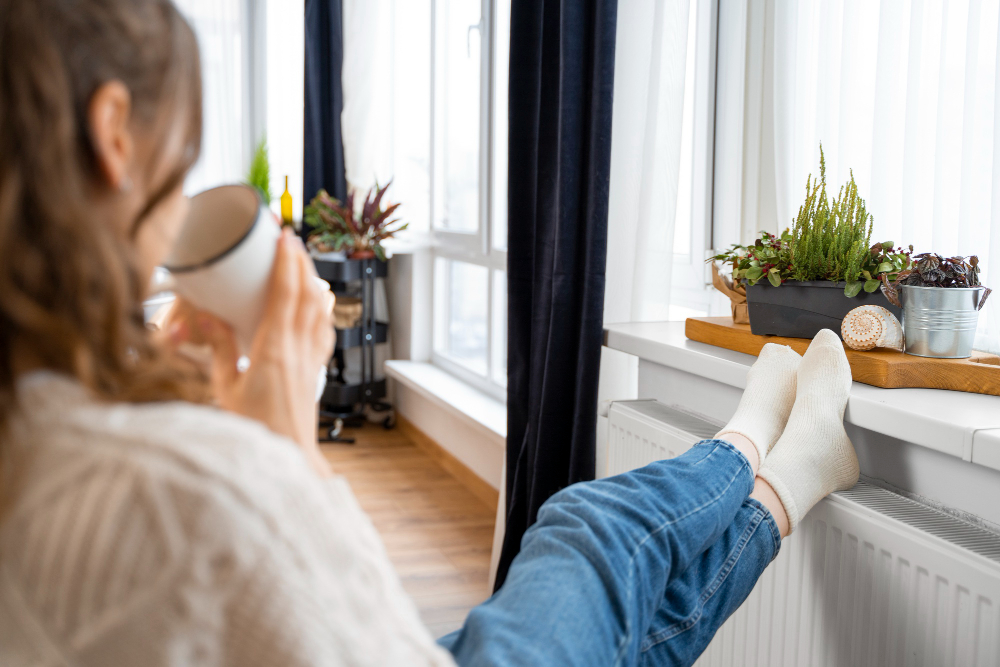 Photo-of-woman-sitting-back-with-tea-and-her-feet-resting-on-heater-using-Dutch-energy