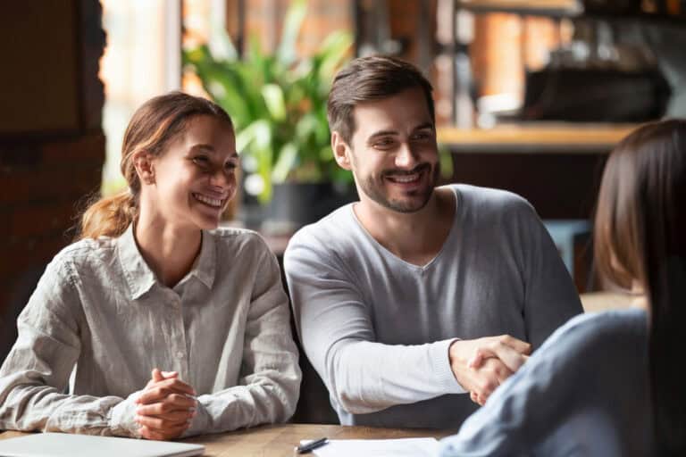 photo-of-man-and-woman-sitting-together-shaking-hands-with-mortgage-advisor-after-Dutch-mortgage-gets-approved-in-the-Netherlands