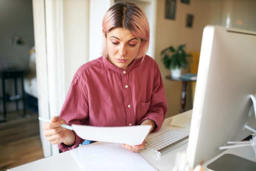 photo-of-woman-reading-employment-contract-with-pink-shirt-sitting-at-desk
