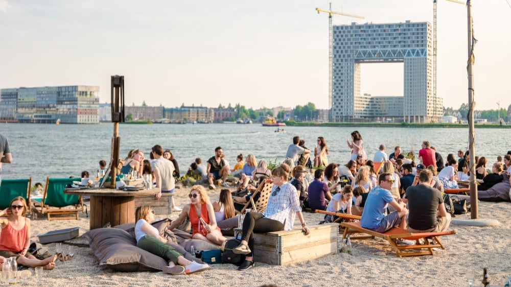 People-sitting-in-sand-at-NDSM-wharf-in-amsterdam-good-spot-to-cycle