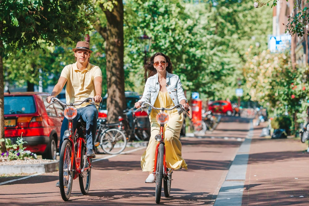 Couple-cycling-through-streets-of-Amsterdam-on-rented-bikes