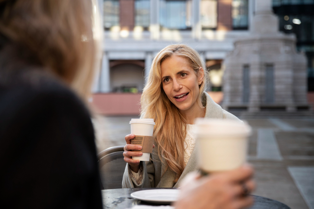 photo-of-woman-asking-another-person-how-are-you-in-Dutch-while-drinking-coffee-outside