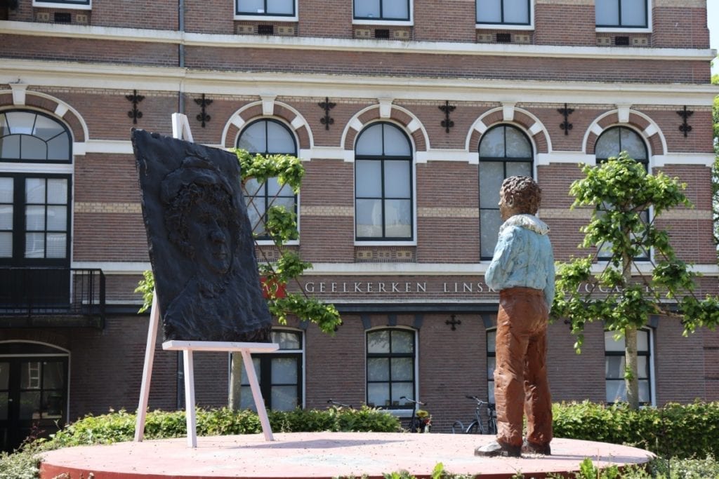 foto da estátua de Rembrandt em Leiden em pé na frente do cavalete