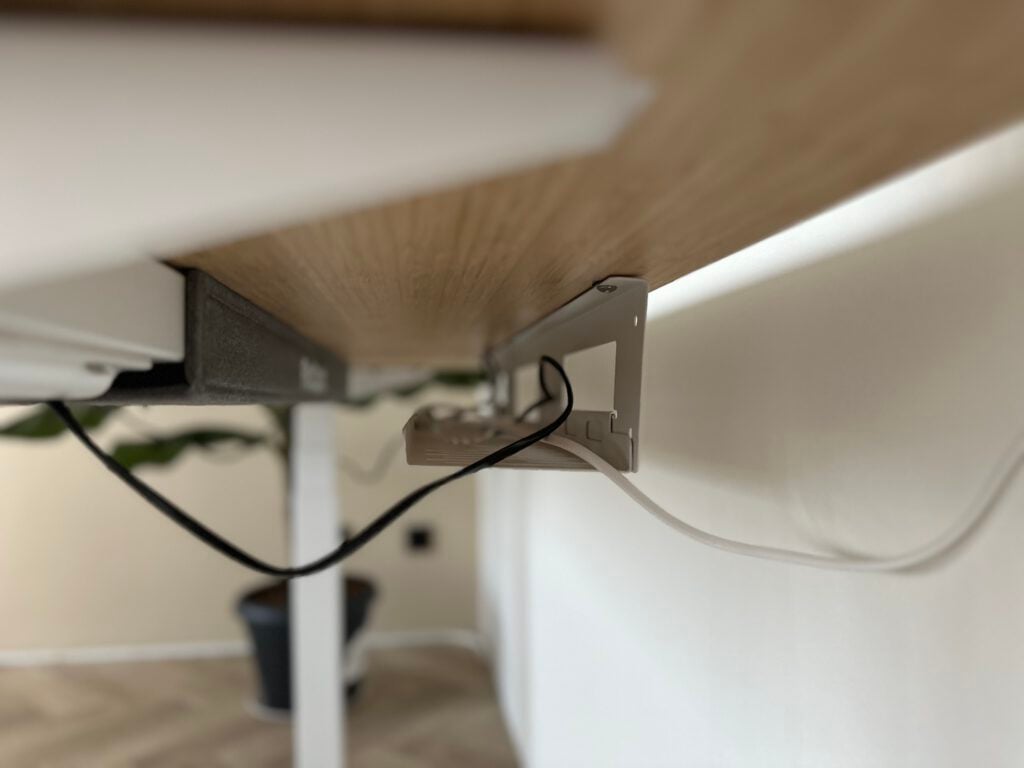 closeup-of-magnetic-cable-organiser-under-desk-with-white-and-black-cord-running-behind