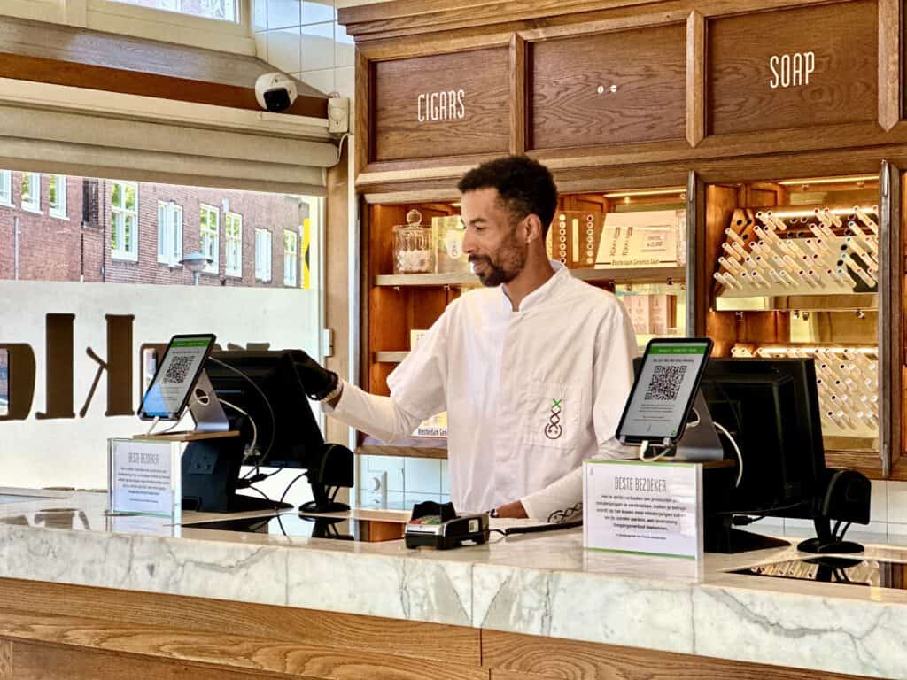 photo-of-friendly-budtender-using-computer-at-coffeeshop-boerejongens-amsterdam-with-old-fashioned-classy-cupboards-in-background