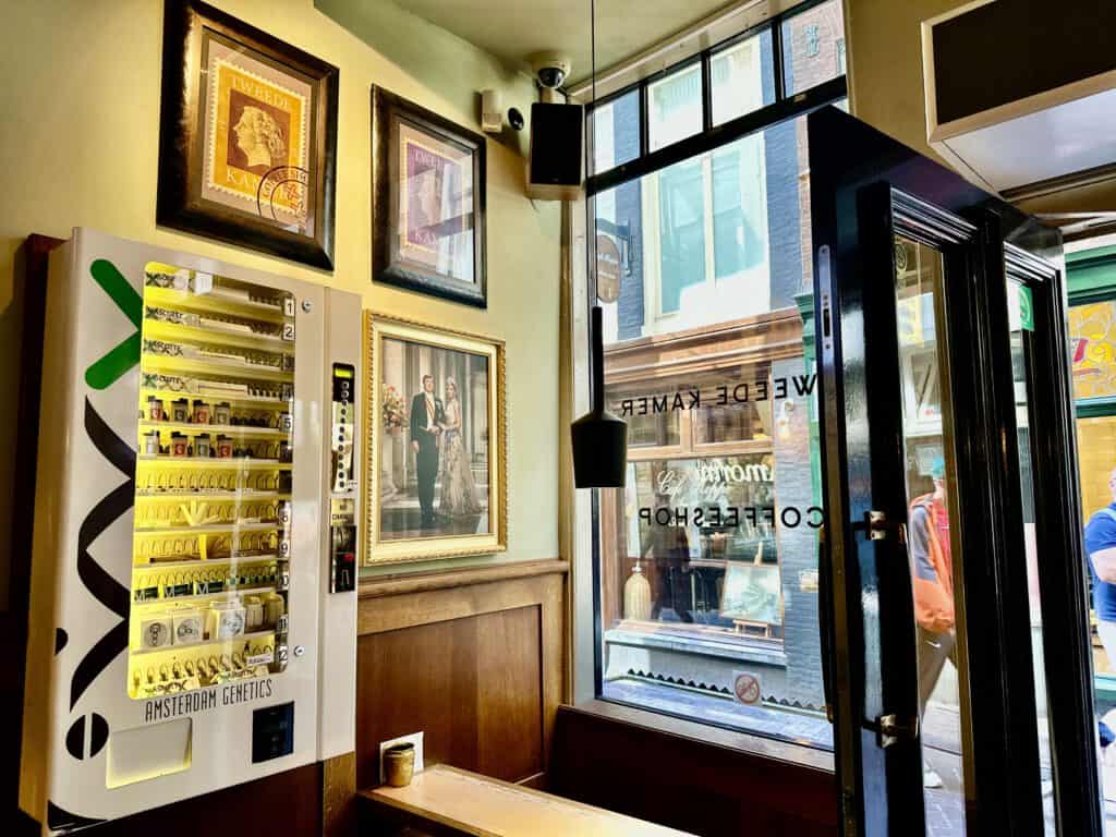 photo-of-interior-of-tweede-kamer-coffeeshop-amsterdam-with-king-and-queen-portraits-on-walls-postage-stamp-logo-and-cannabis-vending-machine-with-window-looking-to-street-outside