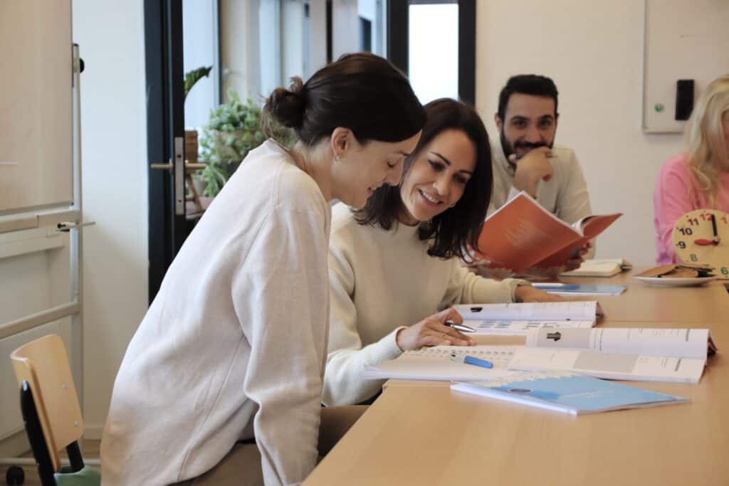 photo-of-three-people-at-table-learning-Dutch-looking-at-pieces-of-paper-and-smiling