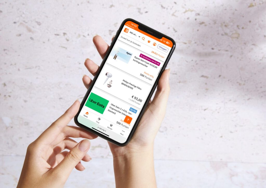 Hand-holding-phone-with-ING-loyalty-store-in-front-of-grey-speckled-background