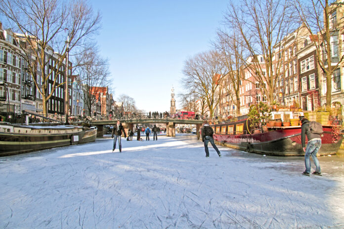 photo-of-frozen-canal-in-amsterdam-with-people-ice-skating-on-sunny-day
