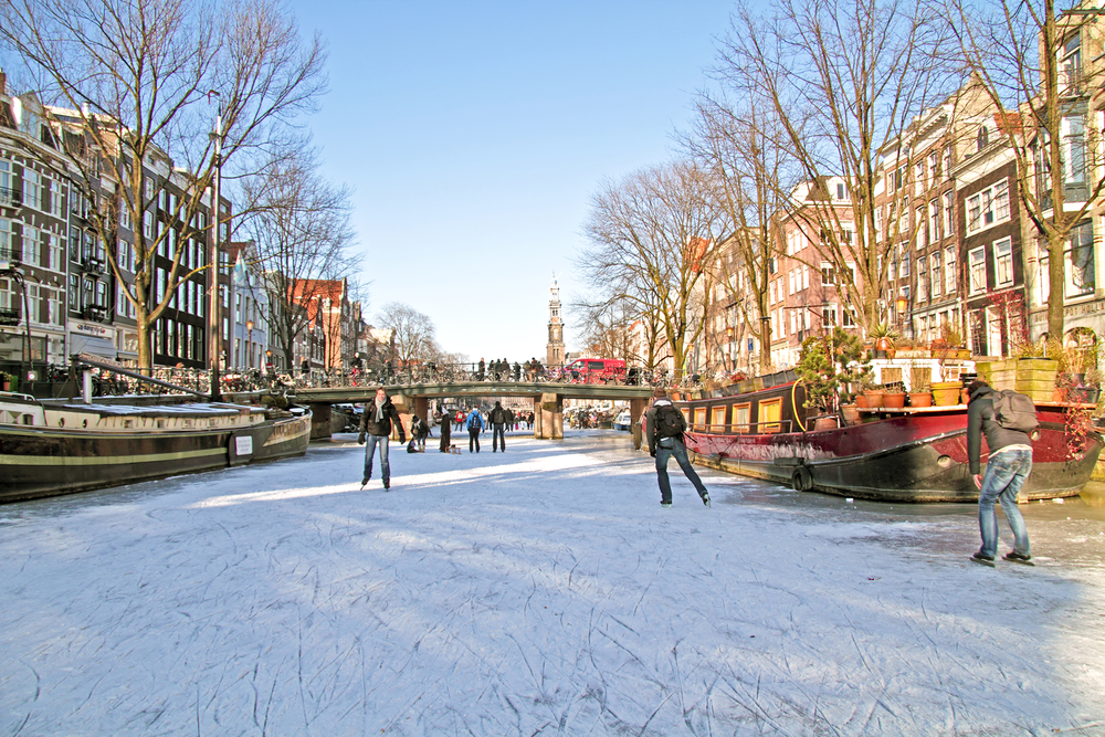 photo-of-frozen-canal-in-amsterdam-with-people-ice-skating-on-a-sunny-day