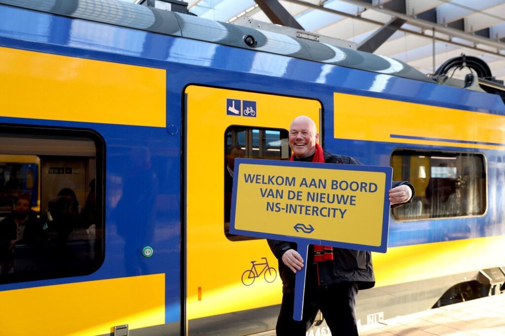 Man holding a sign welcoming people to the Intercity Nieuwe Generatie 