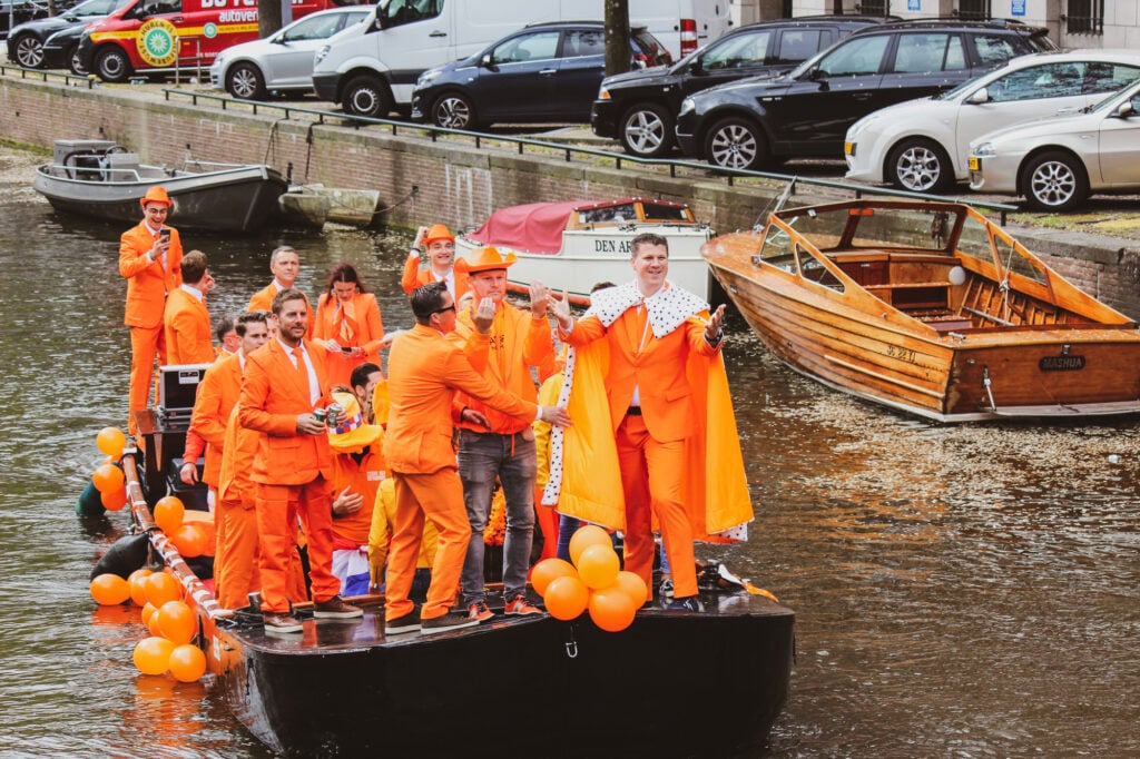 People-celebrating-Kings-Day-on-a-canal-dressed-in-orange