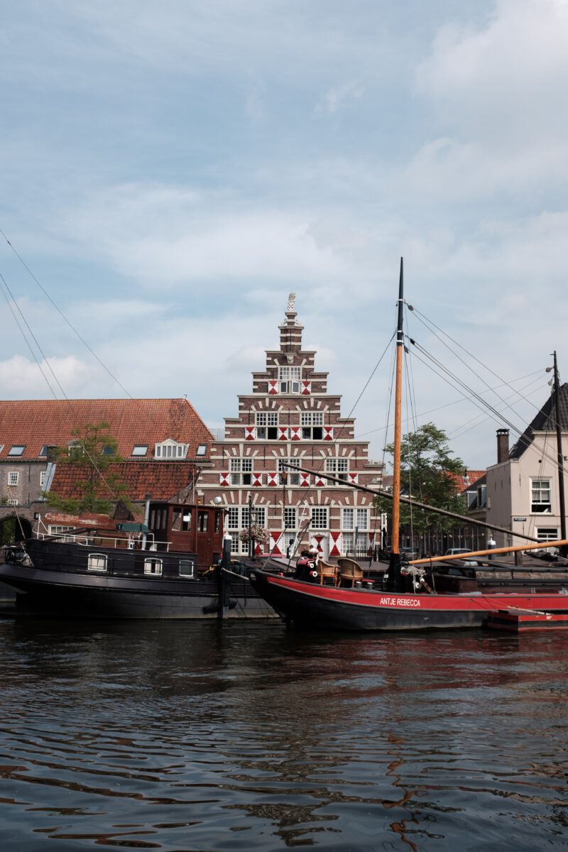 photo-of-a-red-and-black-boat-on-a-canal-in-front-of-a-traditional-dutch-house