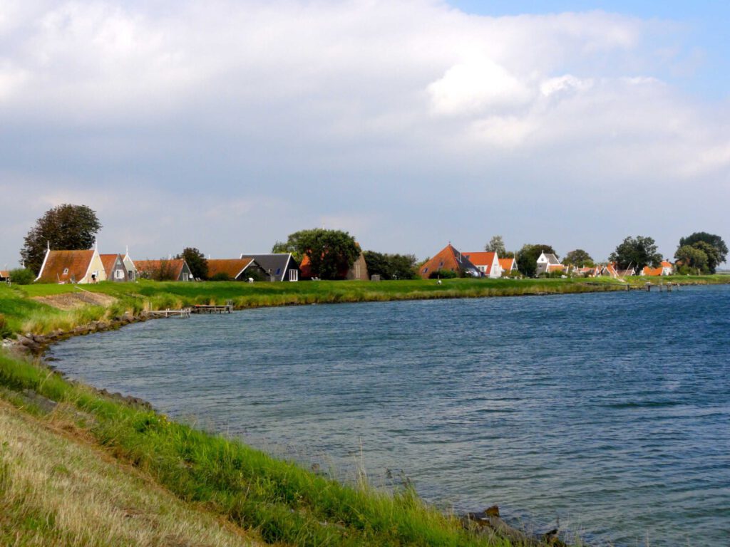 A row of houses curves around the bank of a lake.