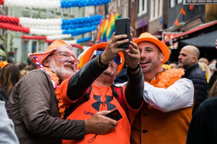 Men-in-orange-clothes-and-hats-taking-selfie-on-King's-Day