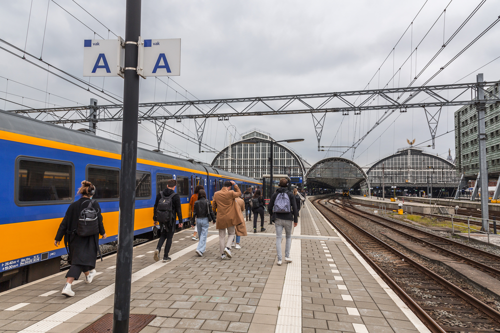 Dutch-train-pulling-into-amsterdam-centraal-station-while-people-walk-on-platform