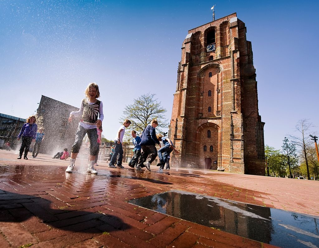 children-play-in-water-with-oldehove-leeuwarden-in-the-distance