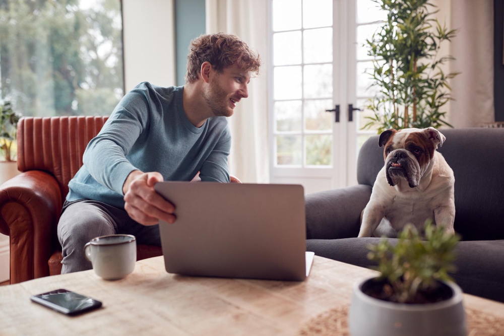 photo-of-man-on-laptop-with-dog-next-to-him-on-chair