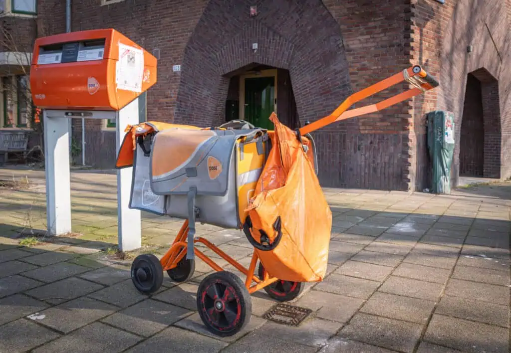 convenient-bright-orange-PostNL-carrier-picking-up-letters-small-packages-to-deliver