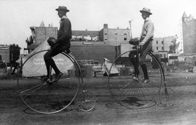 black-and-white-photo-of-two-men-riding-a-penny-farthing