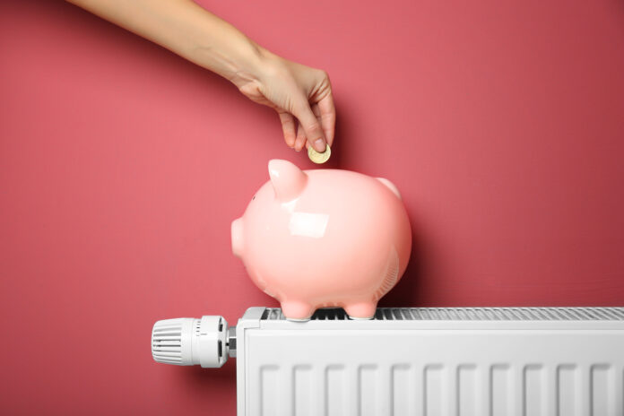 Pink-piggy-bank-on-heater-hand-putting-in-money