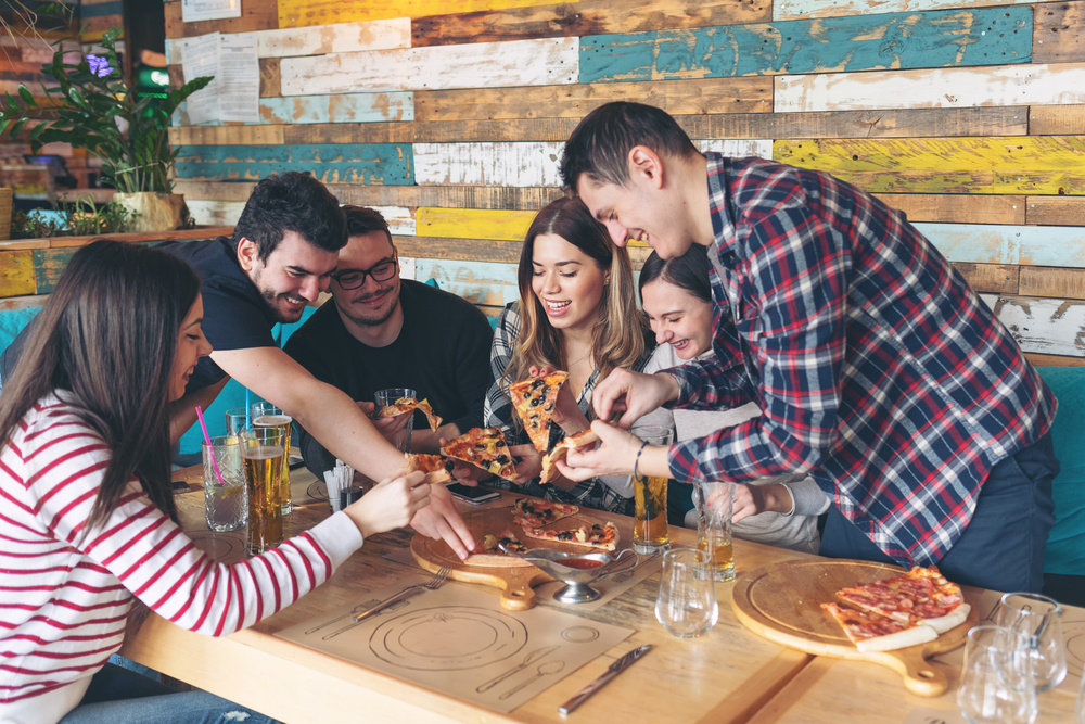 Group-of-friends-around-a-table-enjoying-pizza-and-beers