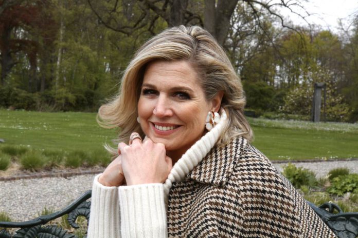 photo-of-queen-maxima-in-garden-wearing-coat-smiling-at-camera-with-head-in-hand