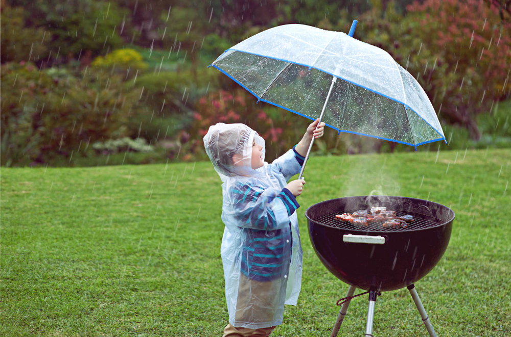 Child-holding-umbrella-above-bbq--in-Dutch-rain-weather-in-summer