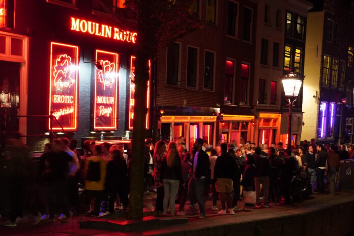 Amsterdam-Red-Light-District-by-night-with-crowded-streets-and-neon-moulin-rouge-sign