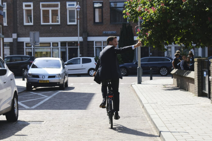 PM Mark Rutte cycling away while waving
