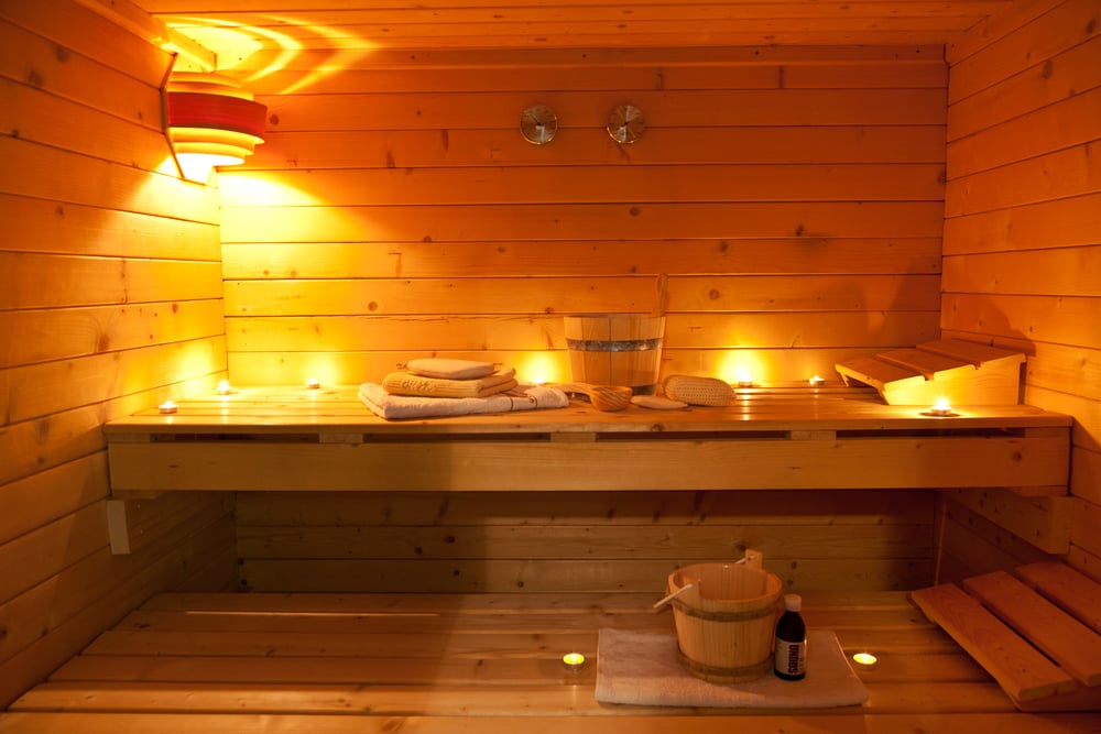 Warmly-lit-interior-of-wooden-sauna-with-buckets-and-laddles