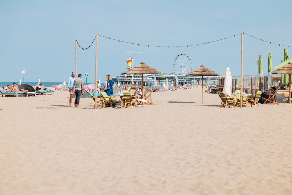 Dutch-beach-in-scheveningen-on-a-sunny-day-with-a-beach-bar-and-ferry-wheel-in-the-back