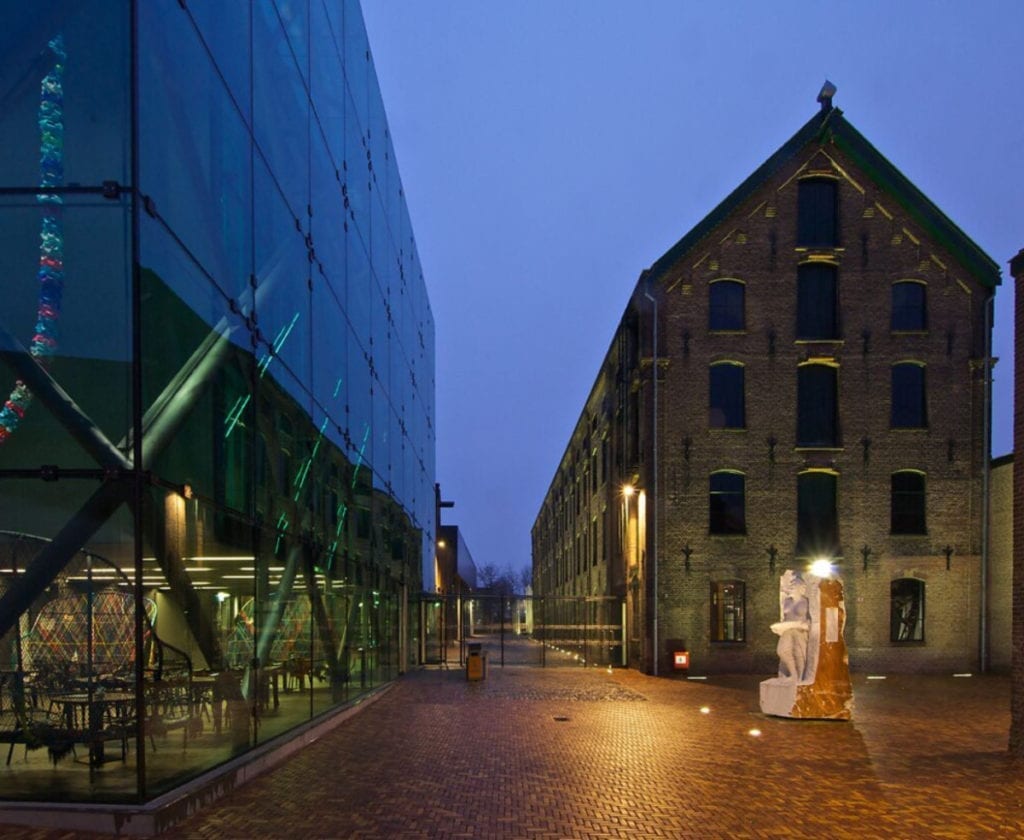 the Textiel museum at night: modern glass building and a heritage warehouse