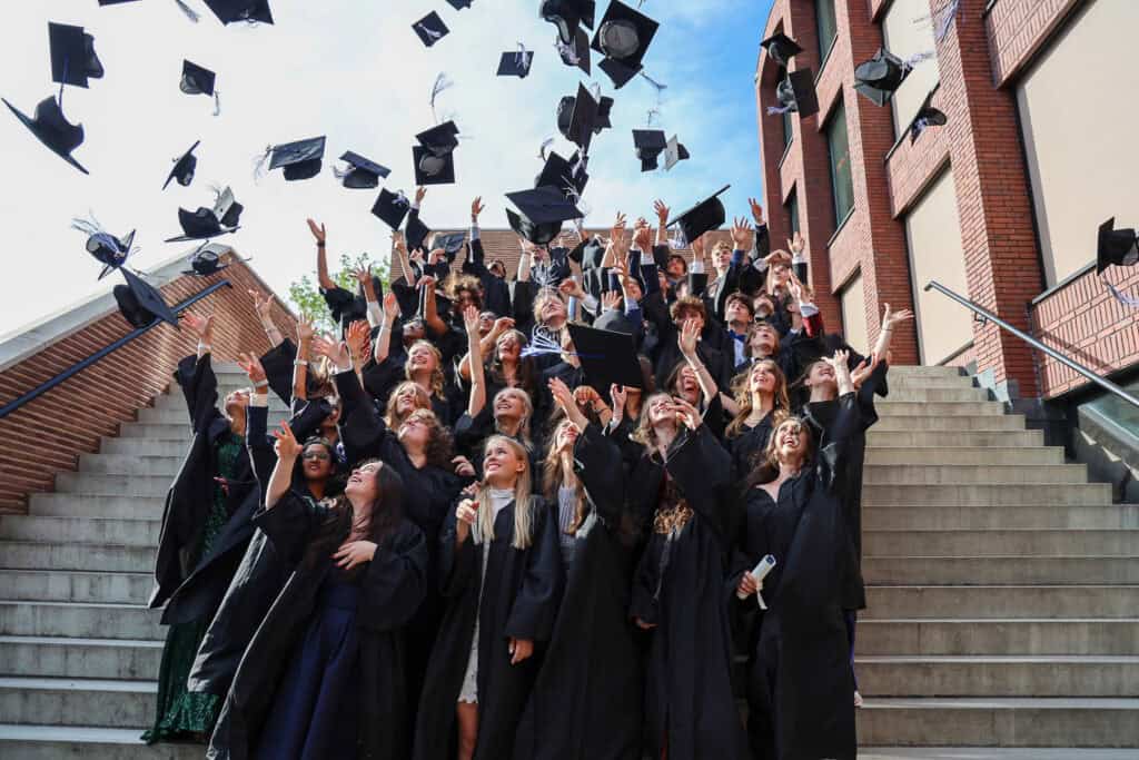 foto de alunos do ensino médio jogando seus chapéus de formatura