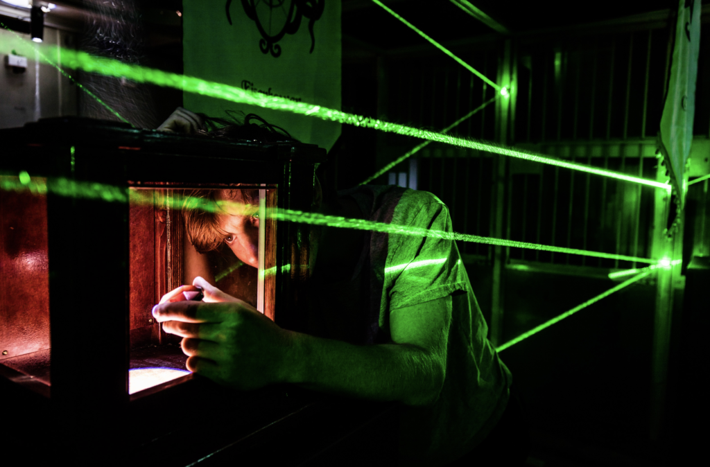 man-carefully-taking-object-from-a-pedistal-protected-by-green-laser-web-glooming-in-the-dark