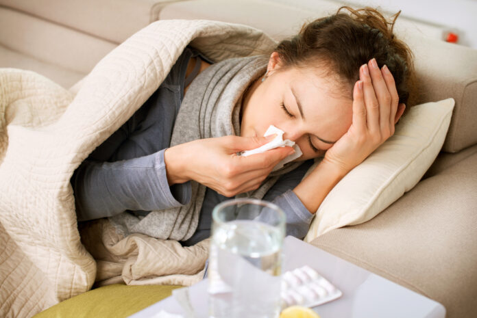 Sick-woman-lying-in-bed-and-blowing-her-nose
