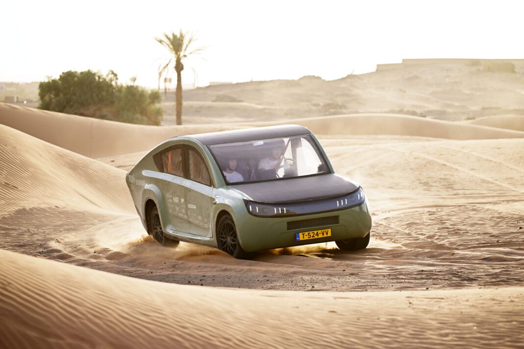 stella-terra-solar-panel-car-created-by-tu-delft-students-driving-across-forest-road-emitting-smoke