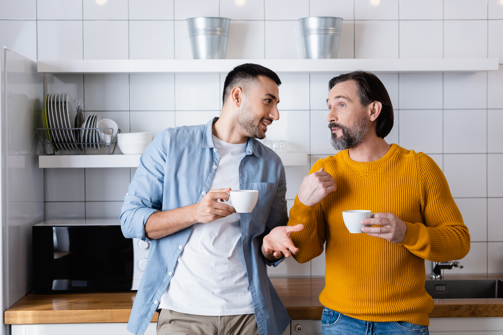 Young-man-next-to-older-man-in-kitchen-with-coffee-cups