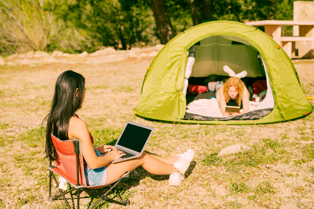 Young-women-sitting-outside-and-in-tent-with-devices