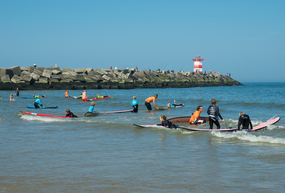 Group-of-people-surfing-in-sea-next-to-Scheveningen-lighthouse
