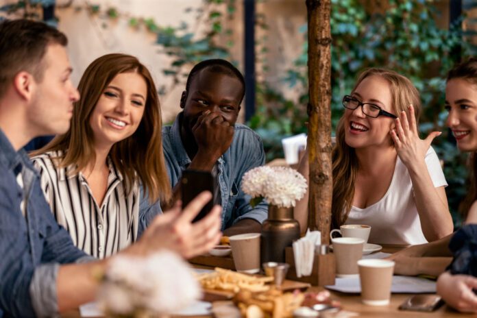 photo-of-people-speaking-Dutch-at-cafe-table-with-friends-laughing-drinking-coffee-green-brown-background