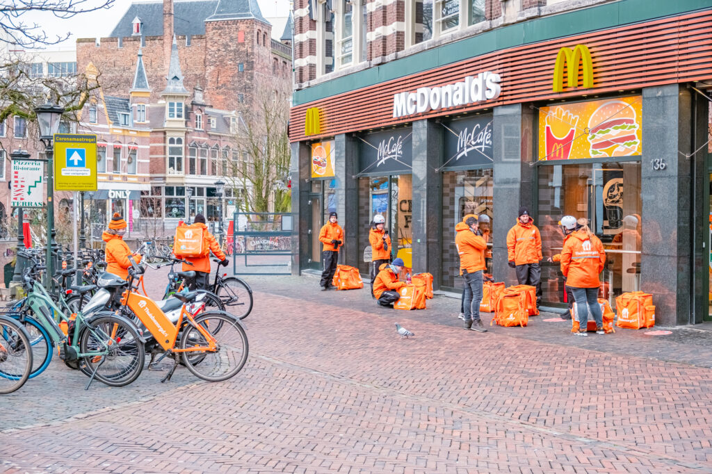 Thuisbezorgd couriers sit restlessly around a Mcdonalds in Utrecht