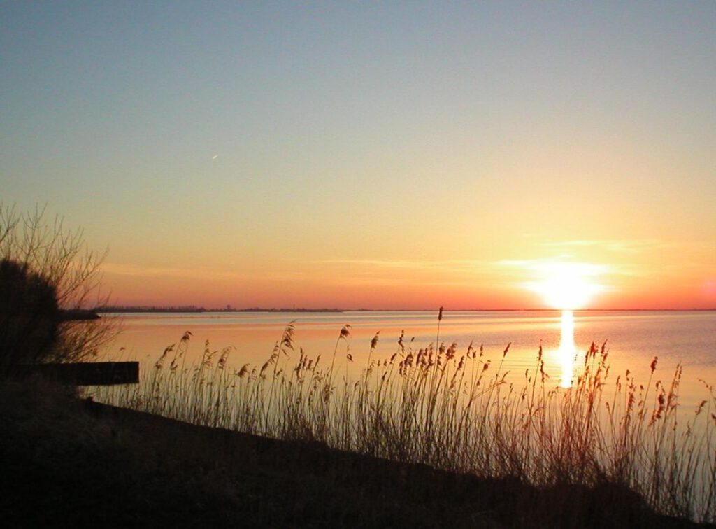 Sunset over Tjeukemeer lake in the Netherlads with hay growing