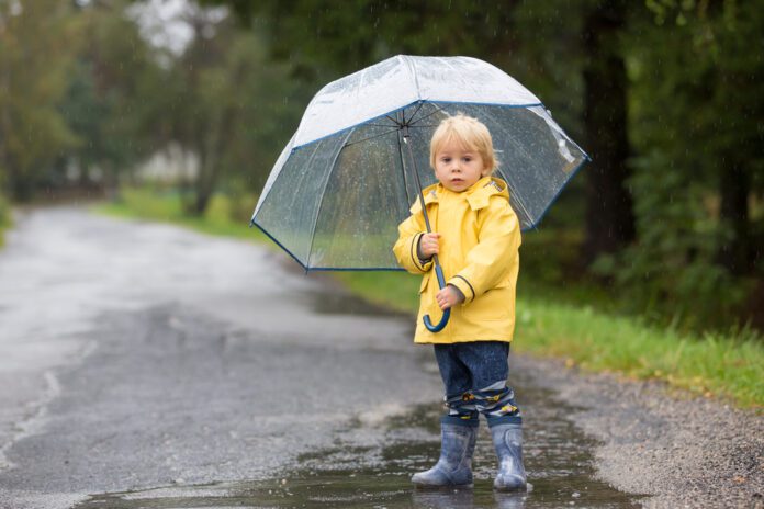 Toddler-standing-in-Dutch-rain-weather-with-umbrella-in-summer