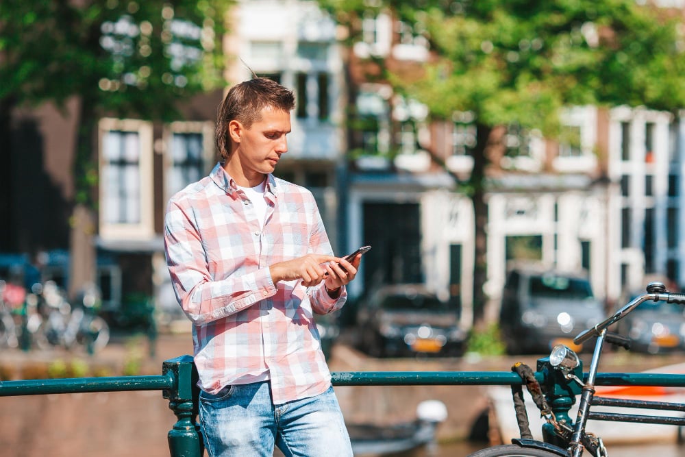 photo-of-man-on-Dutch-canal-looking-at-phone-while-using-Trade-Republic-app-to-help-grow-his-savings-with-best-interest-rates