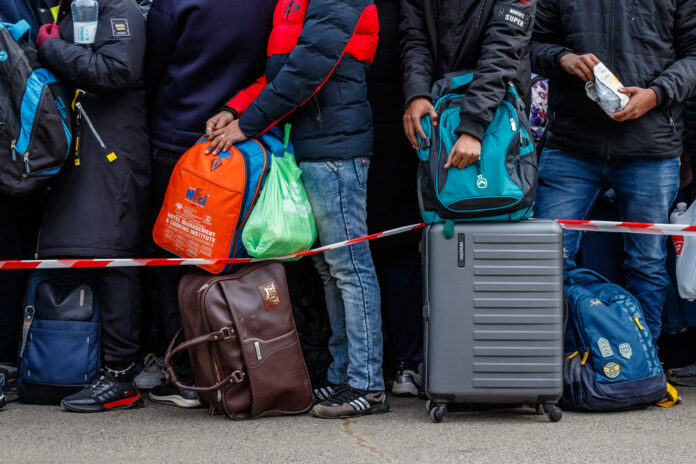 close-up-of-ukrainian-refugees-waiting-in-a-cue-with-bags-and-suitcases