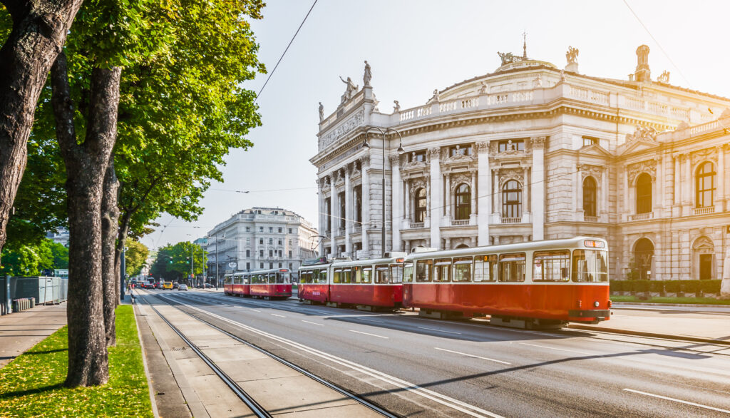 Famous Wiener Ringstrasse with historic Burgtheater (Imperial Court Theatre) and traditional red electric tram at sunrise with retro vintage Instagram style filter effect in Vienna, Austria — reached by international train form Amsterdam