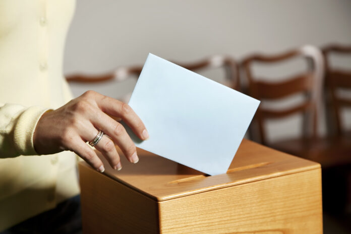 Female-hand-placing-voting-slip-in-ballot-box-for-dutch-municipal-elections