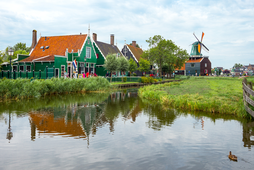 Colourful-green-wooden-Dutch-houses-and-windmill-with-water-and-grass